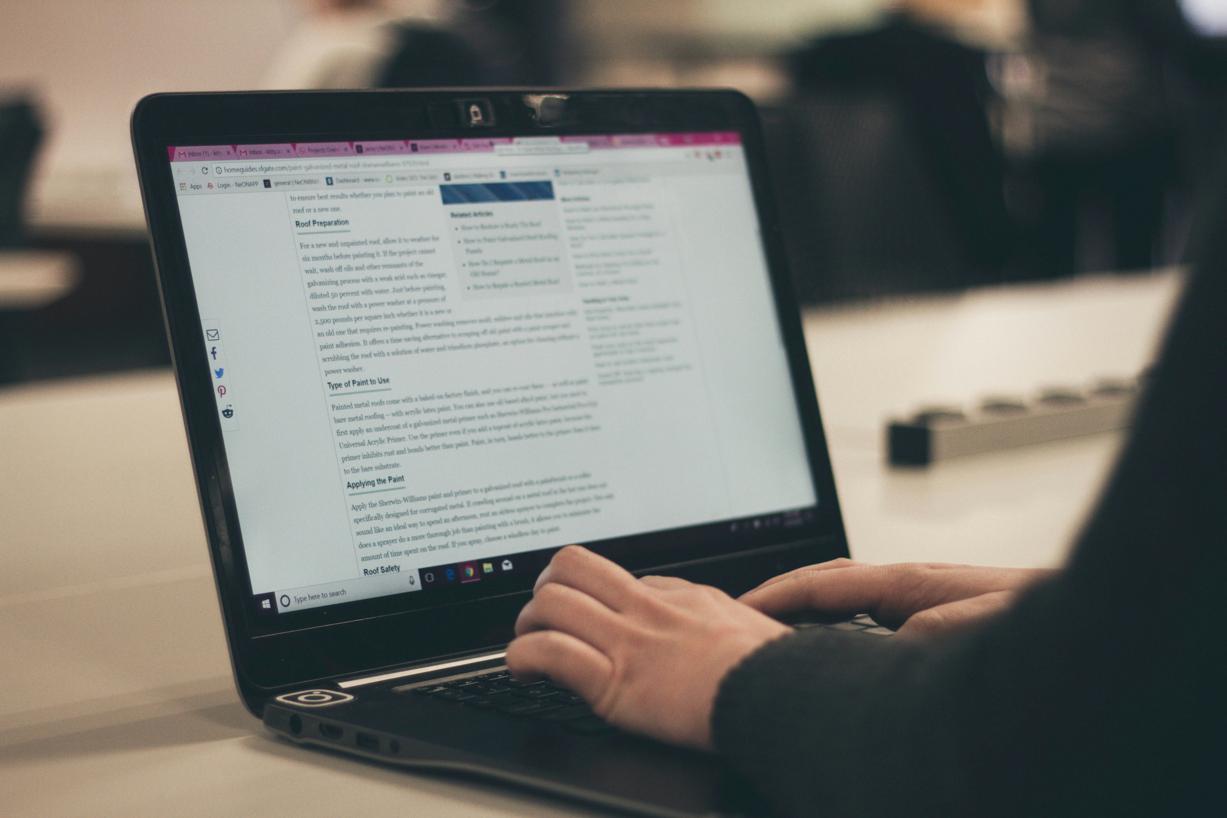 A person is typing on a laptop with an article about the best blogging platform for photographers displayed on the screen.