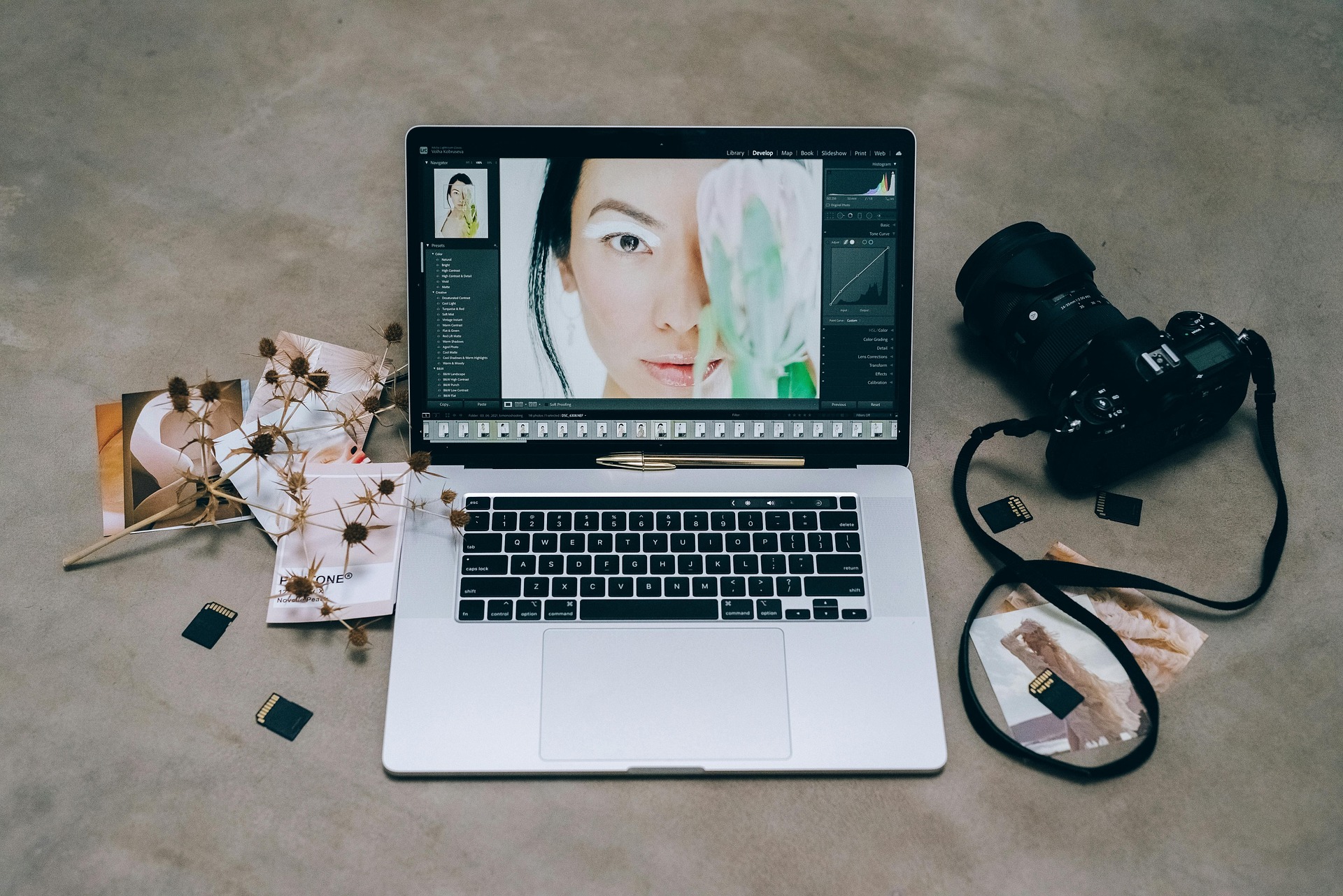 A laptop sits on a table open to a culling software for photographers with a camera and memory cards scattered about