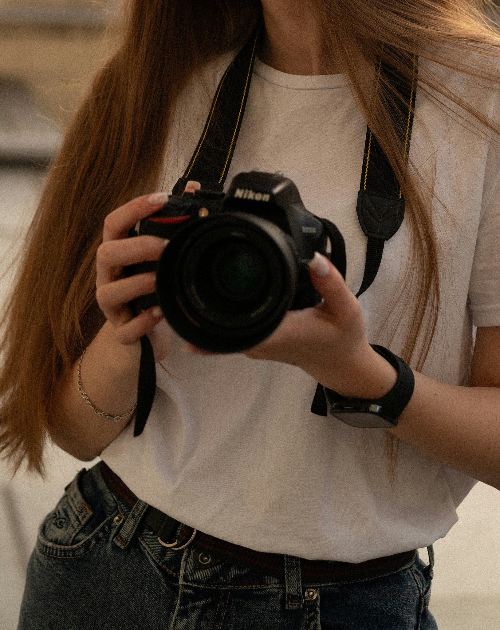 Details of a woman holding a camera before she explores Aftershoot vs Imagen